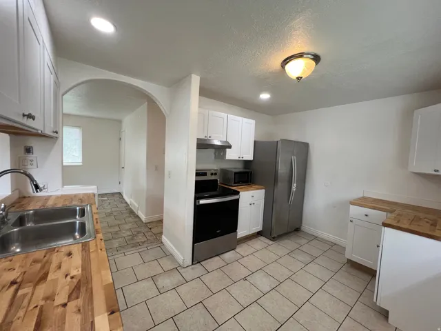 Kitchen featuring wood-finish countertops, white cabinetry, stainless steel appliances, and tile flooring