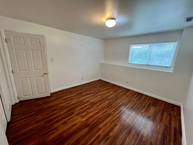 Wood-finish flooring, white walls, and a multi-panel interior door