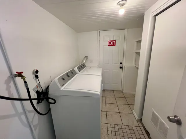 Walk in basement entrance. Tile flooring, built-in shelving, white paneled door, and ceiling-mounted light fixture