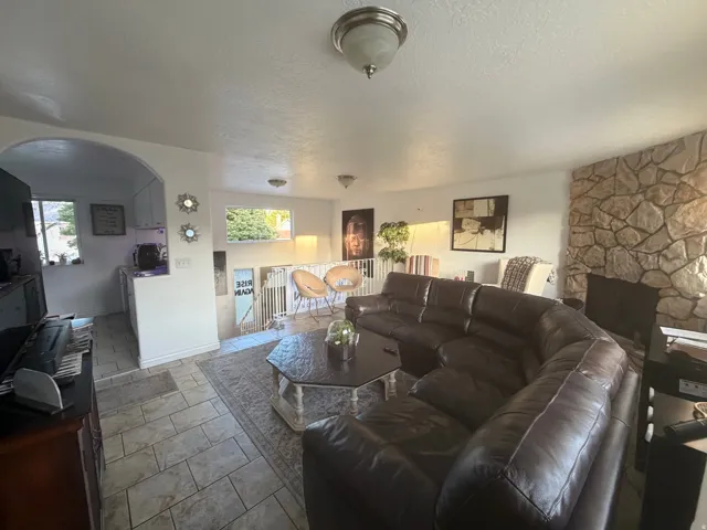 Stone-clad accent wall with fireplace, arched doorway, and tiled flooring