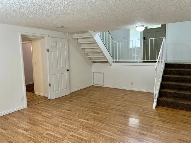 Wood-finish flooring, white painted walls, multi-level staircase with white metal railing, and recessed lighting