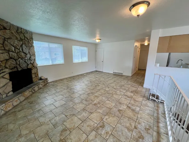 Stone-clad fireplace with hearth, tile flooring, and multiple windows