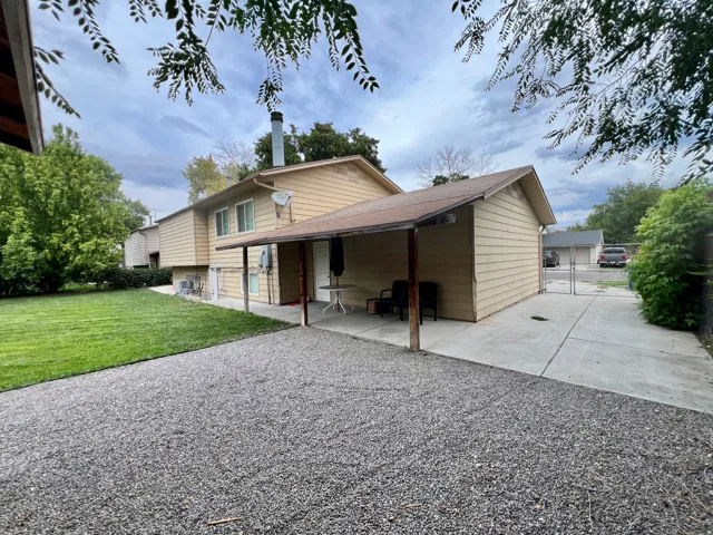 Paved concrete patio with a covered section and adjacent gravel parking area and concrete RV parking