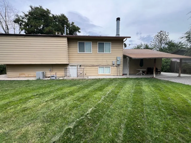 Expansive lawn area with a covered patio, RV parking, basement entrance.