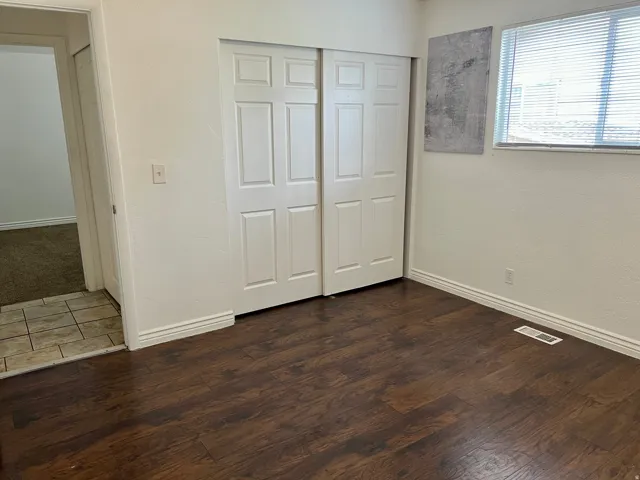 Wood-finish flooring throughout the room, featuring white baseboards and white walls