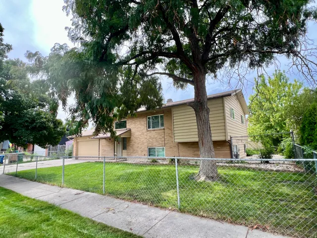 Two-story exterior with brick and siding finishes, featuring an attached garage, fenced yard, RV or extra parking, and a mature front yard tree