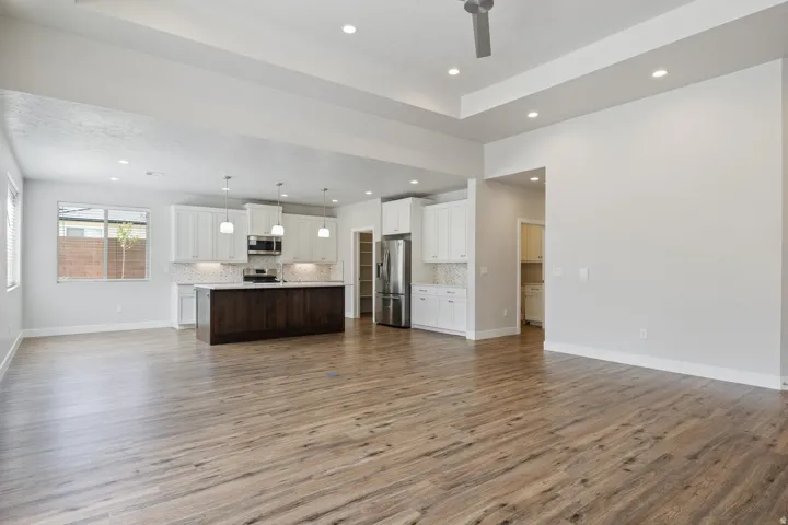 Open-concept living space with wood-finish flooring, recessed lighting, and a tray ceiling