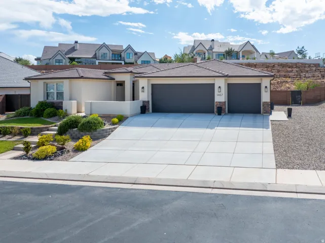Contemporary stucco exterior with a tile roof, dual garage doors, and a concrete driveway