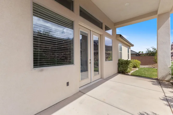 Covered patio with concrete flooring, stucco exterior, dual pane windows, and a landscaped yard