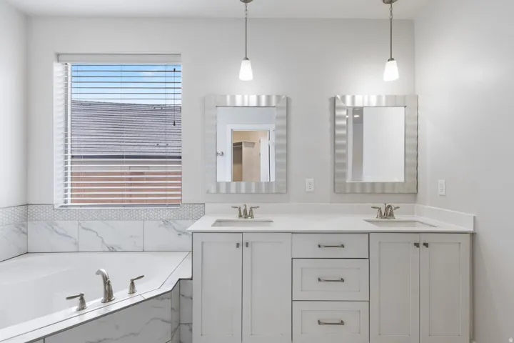 Dual vanity with white cabinetry, quartz countertops, and brushed nickel hardware