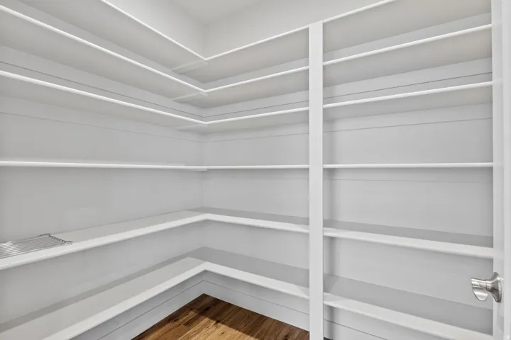 Expansive pantry featuring wrap-around shelving, vertical shelving, and wood-finish flooring