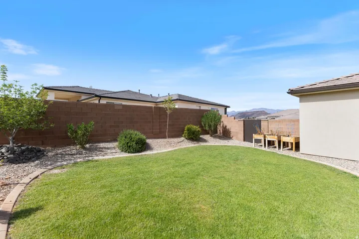 Expansive backyard featuring a manicured lawn, gravel landscaping, and mature shrubbery