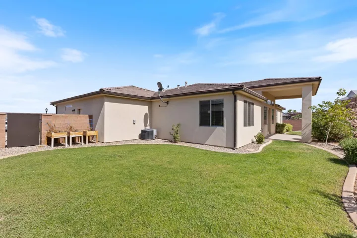 Expansive backyard with a manicured lawn, established landscaping, and a covered patio area