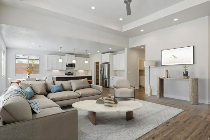 Open-concept living space featuring wood-finish flooring, recessed lighting, and a tray ceiling