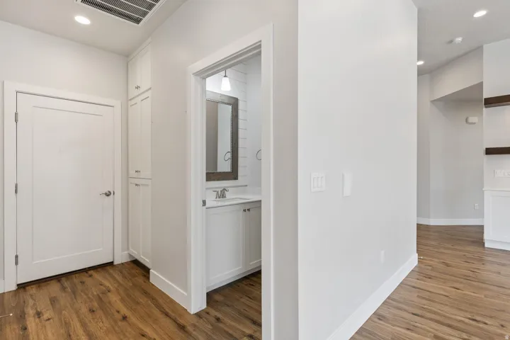 Wood-finish flooring, white walls, and recessed lighting
