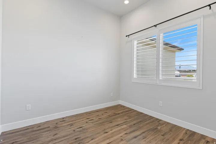 Spacious room with wood-finish flooring, white baseboards, and light gray walls