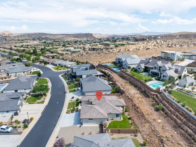 Aerial perspective of a neighborhood featuring a curved street, multiple single-family residences, and natural rock landscaping