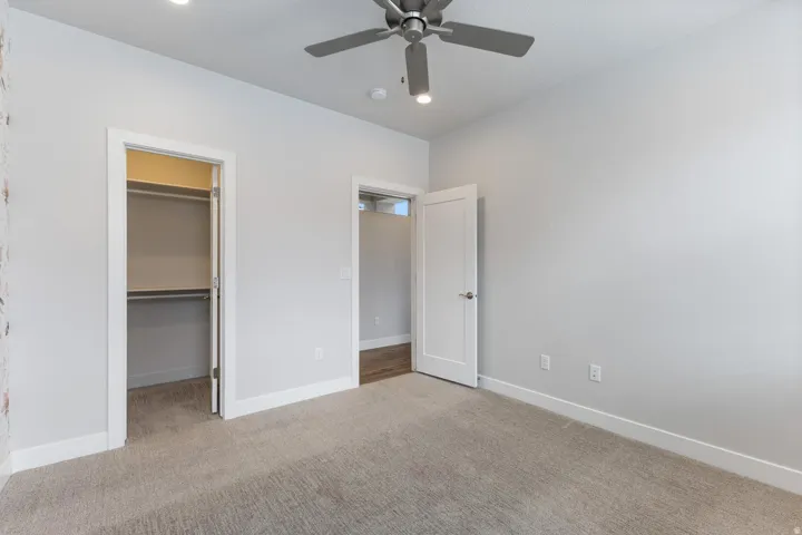 Recessed ceiling lighting, ceiling fan, plush carpet flooring, two-panel interior doors, and built-in closet shelving