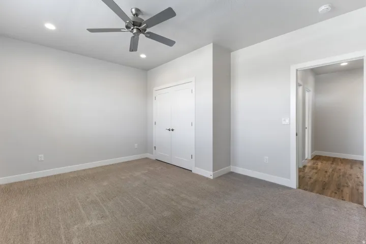 Neutral tone wall paint, recessed ceiling lighting, ceiling fan, and carpet flooring