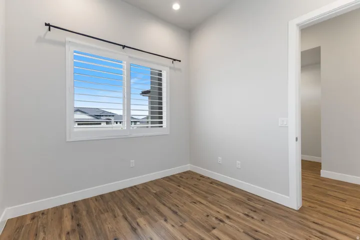 Wood-finish flooring, recessed lighting, and a window with plantation shutters