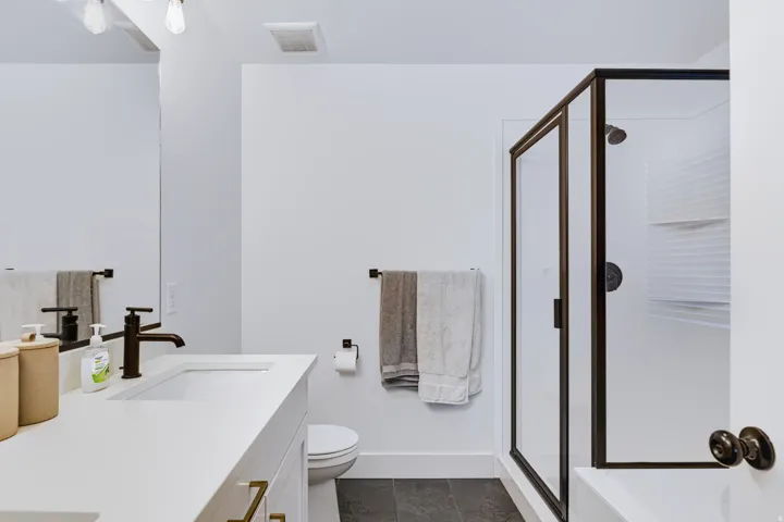 White vanity with an integrated sink, bronze-finish faucet, and gold-tone drawer pulls