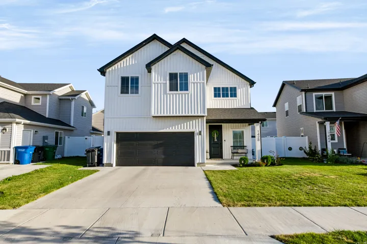 Two-story residence featuring white vertical siding, black trim accents, a two-car garage, and a covered entryway