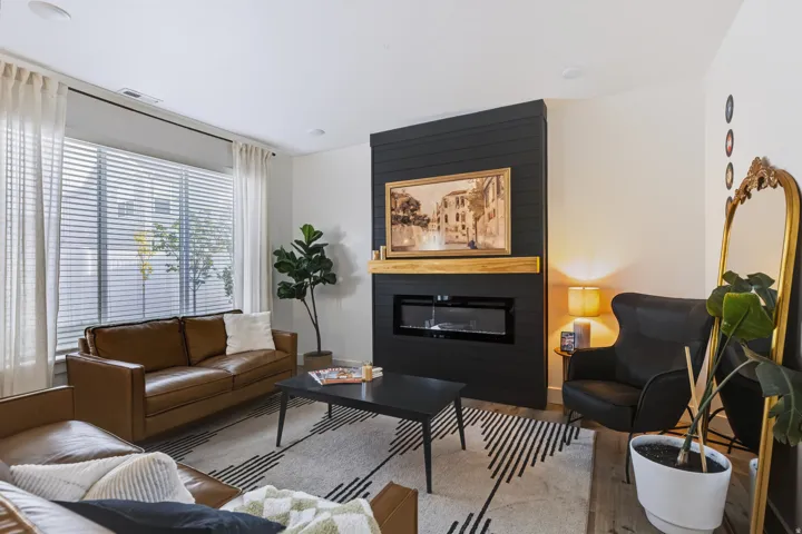 Living area featuring a modern linear fireplace with a wood mantel, dark shiplap accent wall, and recessed lighting