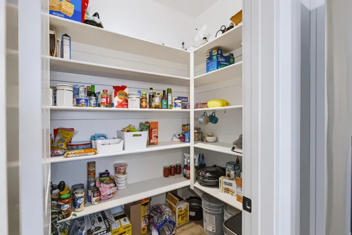 Walk-in pantry featuring white shelving and white walls