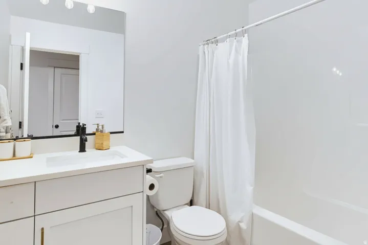 White vanity with a single basin sink, matte black faucet, and a large wall-mounted mirror