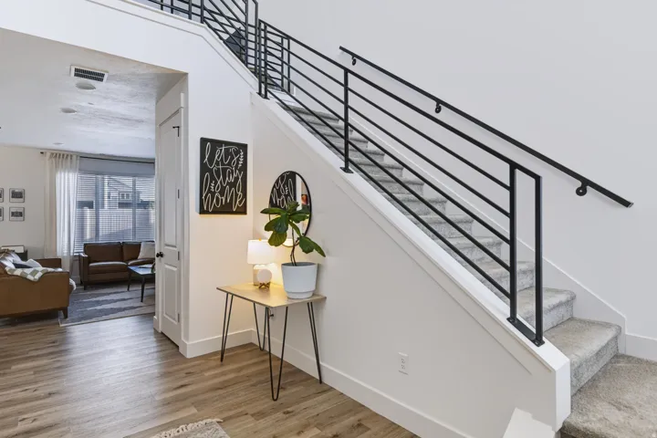 Wood-finish flooring, a contemporary black metal stair railing, and carpeted stairs