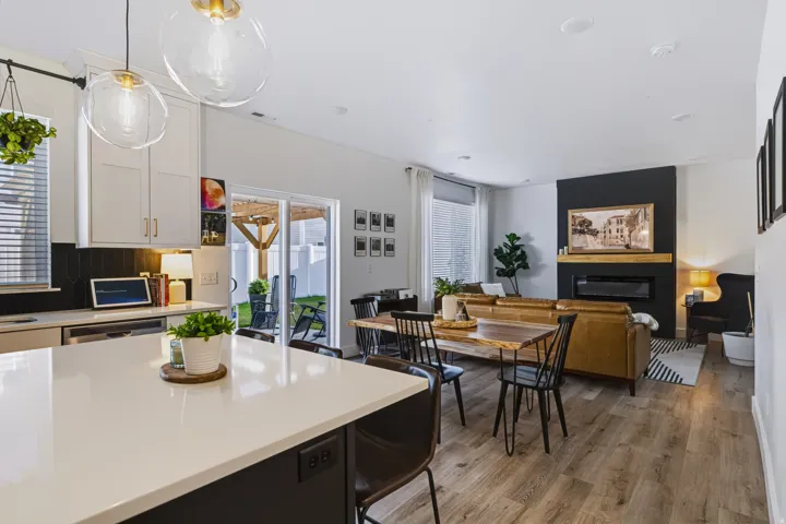 Kitchen island with a light-toned countertop, wood-finish flooring, built-in fireplace with a wood mantle, and sliding glass door to the backyard