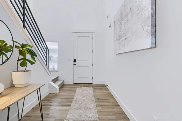 High ceilings, wood-finish flooring, two-panel solid core entry door with smart lock, and staircase with black metal railing
