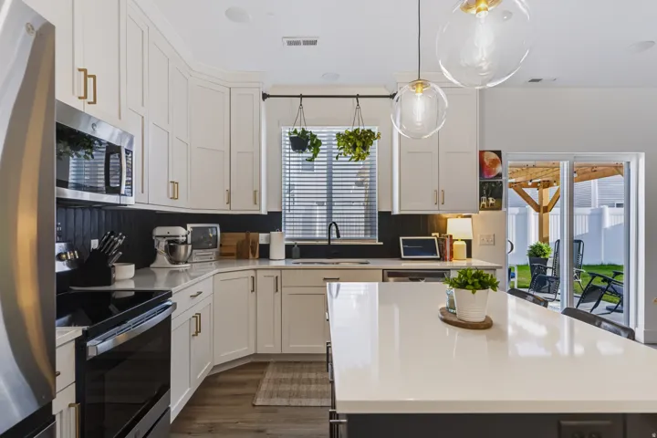 White shaker cabinetry, stainless steel appliances, solid surface countertops, wood-finish flooring, and sliding glass door