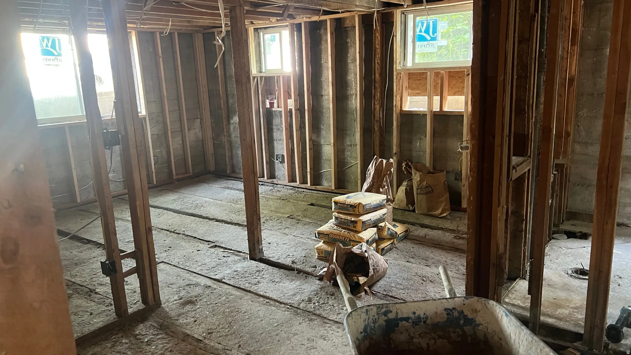 View of kitchen with living room visible through the studs on left and bathroom through studs on right.
