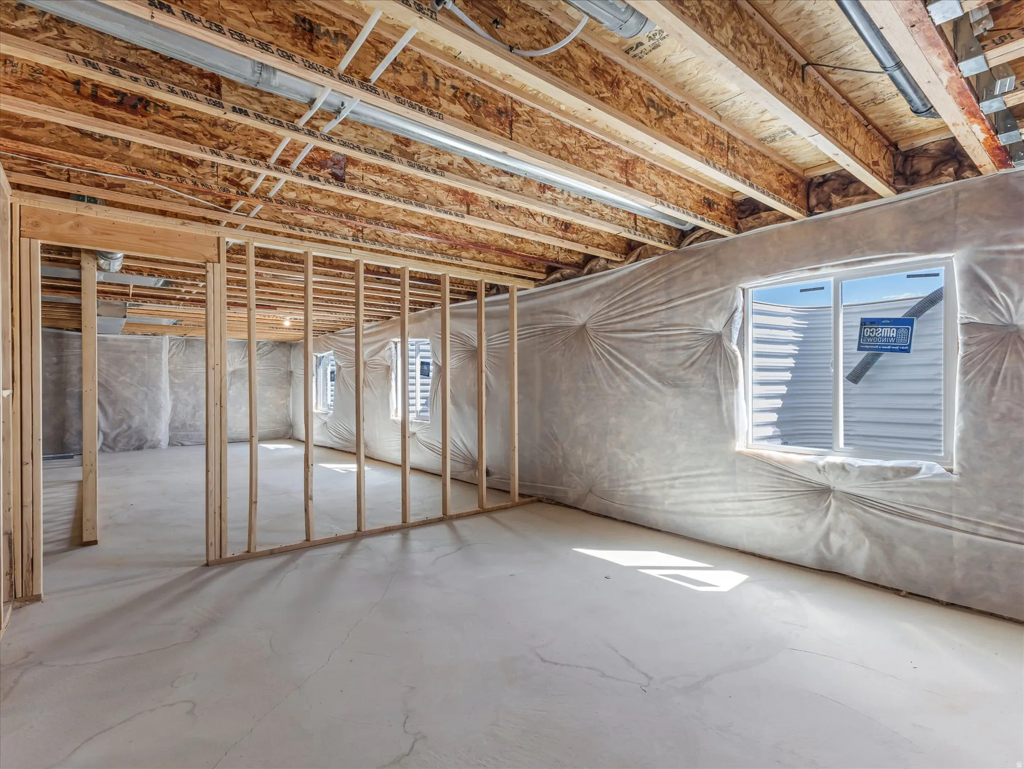 Unfinished basement with concrete flooring and exposed wood framing