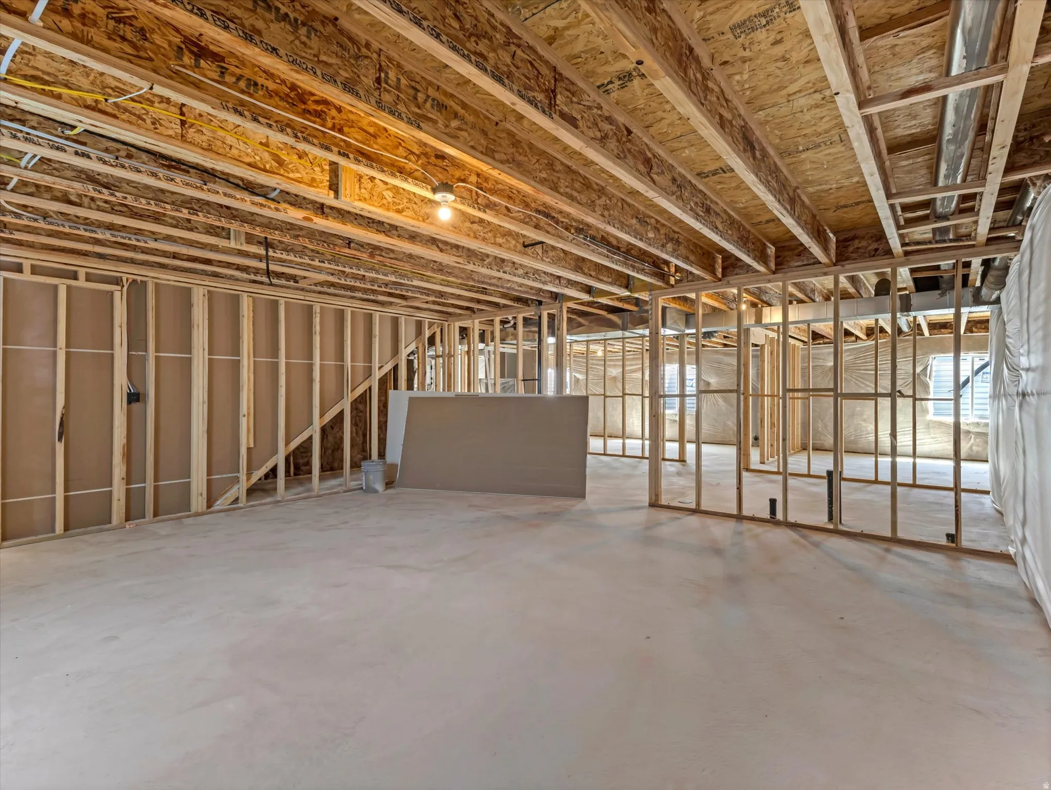 Unfinished basement with concrete flooring, exposed wood framing, exposed ceiling joists, and visible wiring