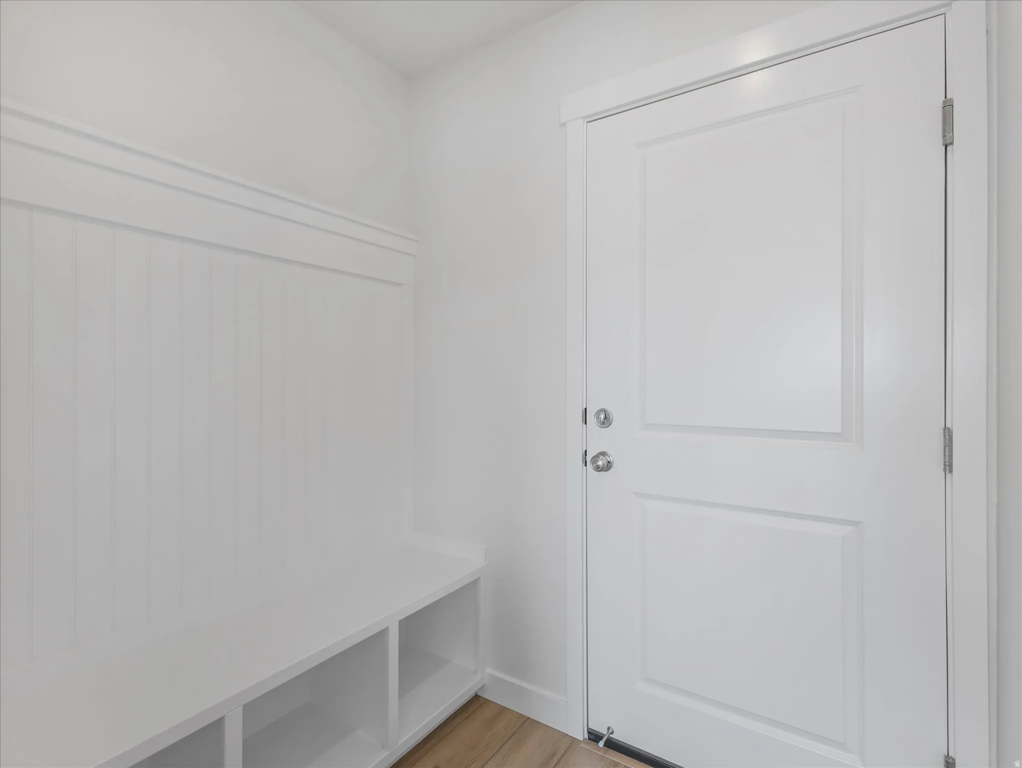 Built-in bench with integrated shelving, beadboard wall paneling, and wood-finish flooring