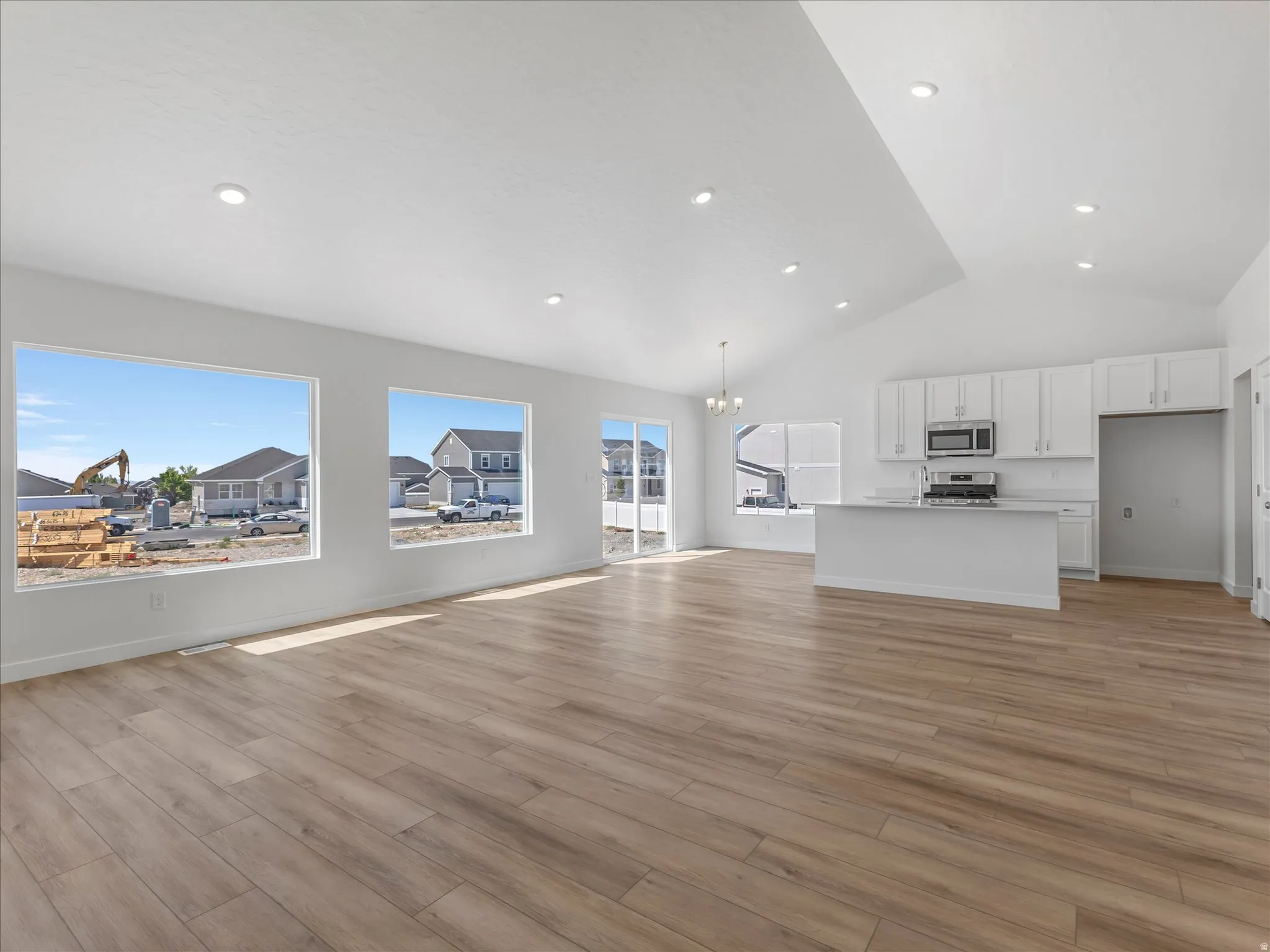 Open-concept living space featuring wood-finish flooring, recessed lighting, and vaulted ceilings