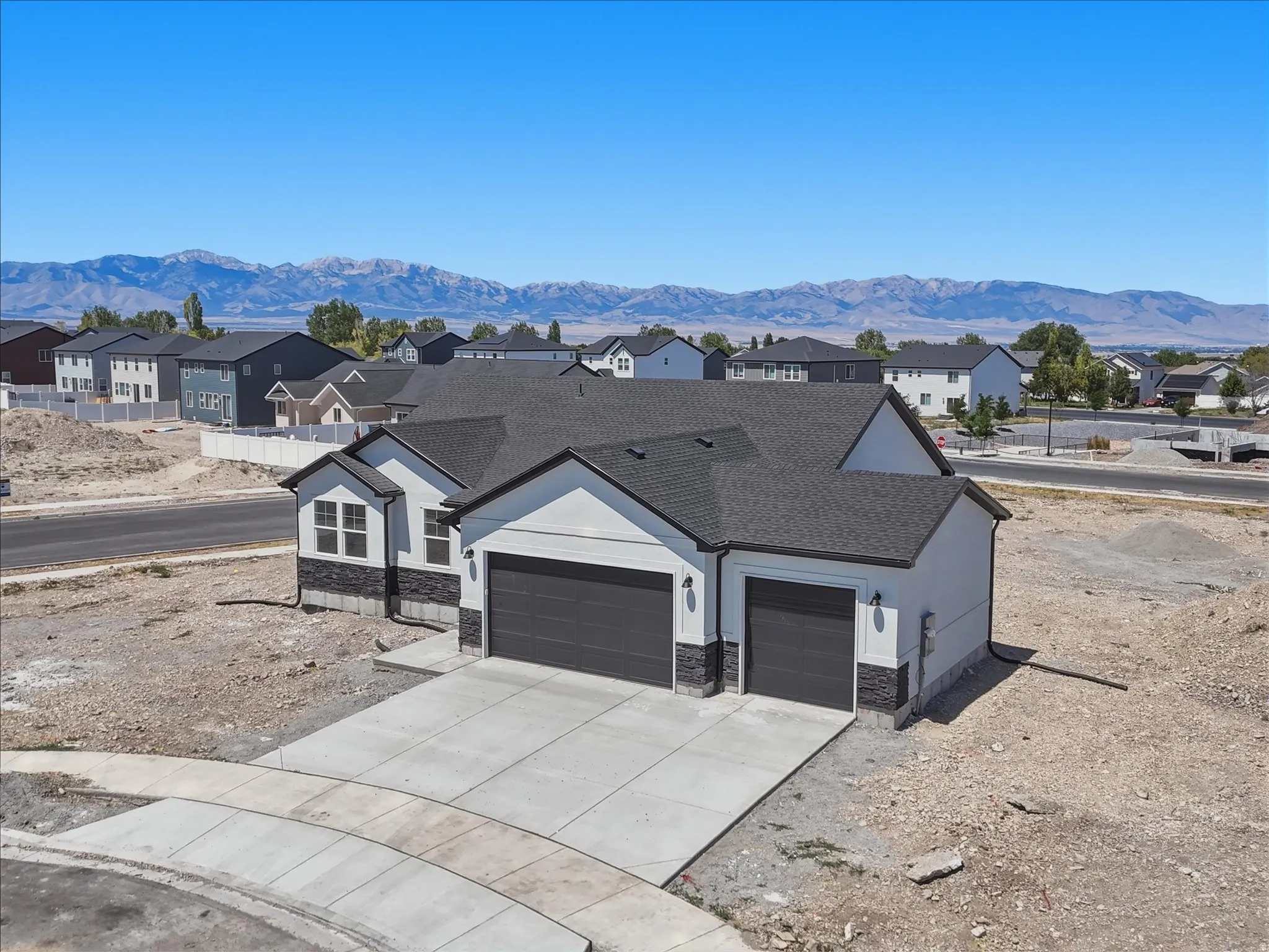Contemporary home exterior with a two-car garage, an additional single-car garage, and dark gray garage doors