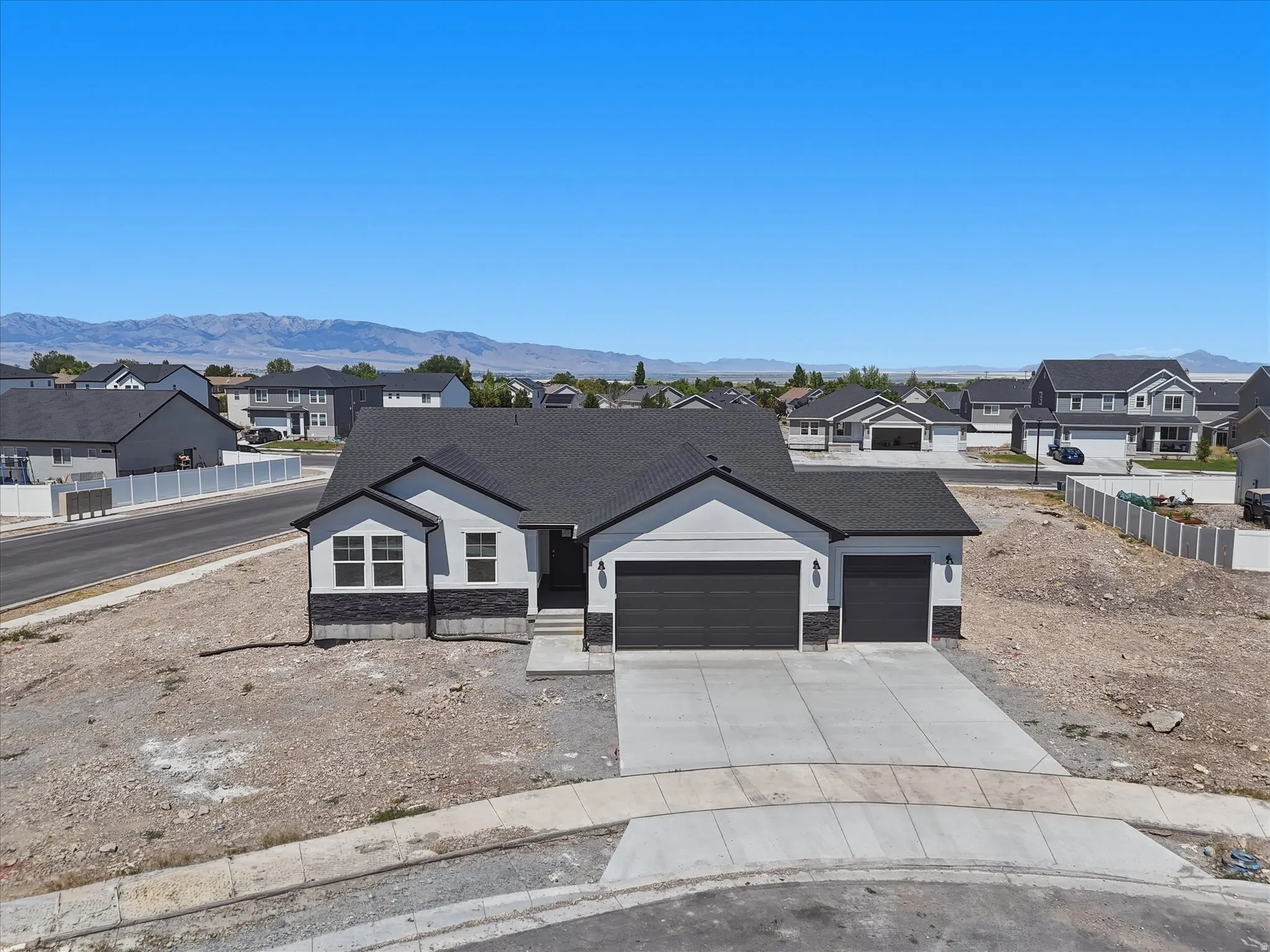 Contemporary single-story residence with a dark shingle roof, light-colored siding, and dark stone accents
