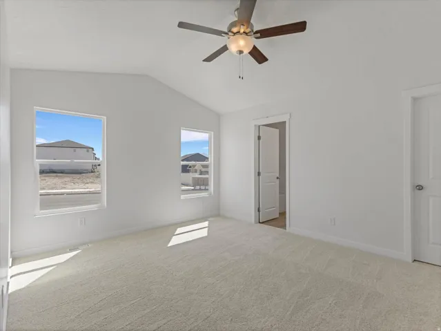 Vaulted ceiling with a ceiling fan, two windows, wall-to-wall carpeting, and white interior doors