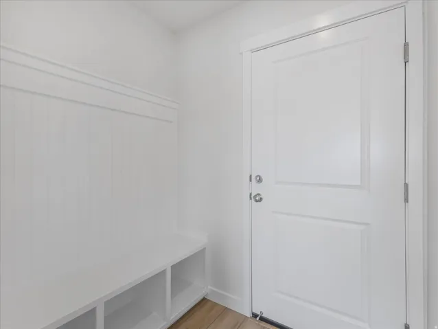 Built-in bench with integrated shelving, beadboard wall paneling, and wood-finish flooring