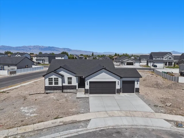 Contemporary single-story residence with a dark shingle roof, light-colored siding, and dark stone accents