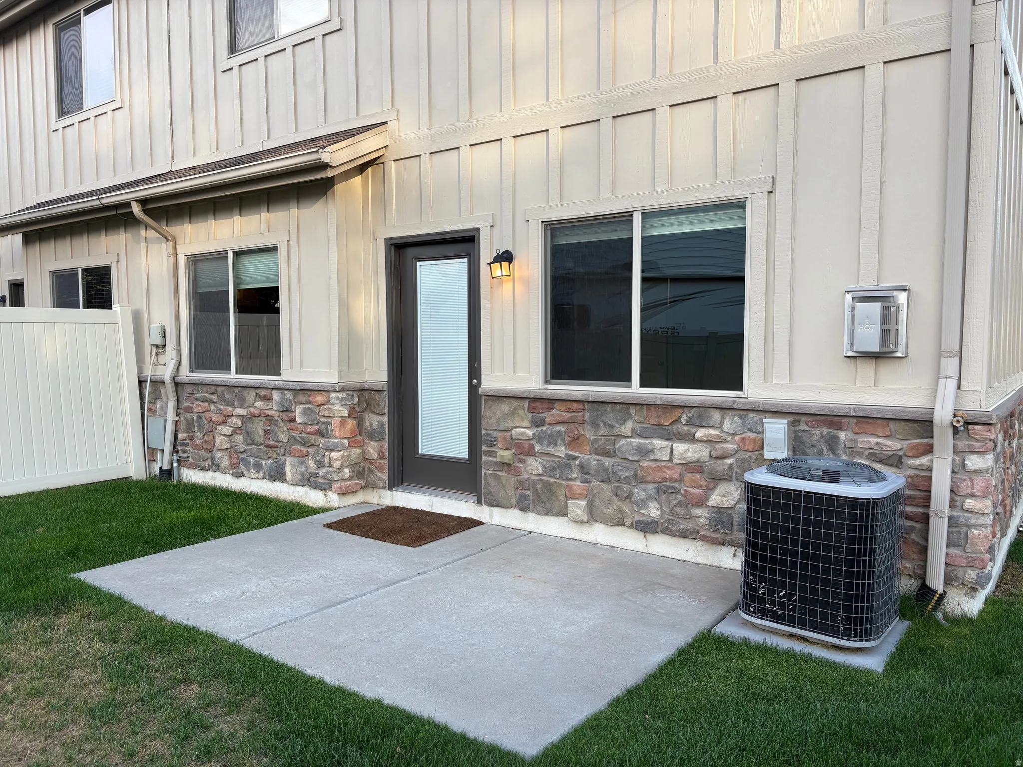 Ground-level patio with concrete surfacing, exterior lighting fixture, and a privacy fence