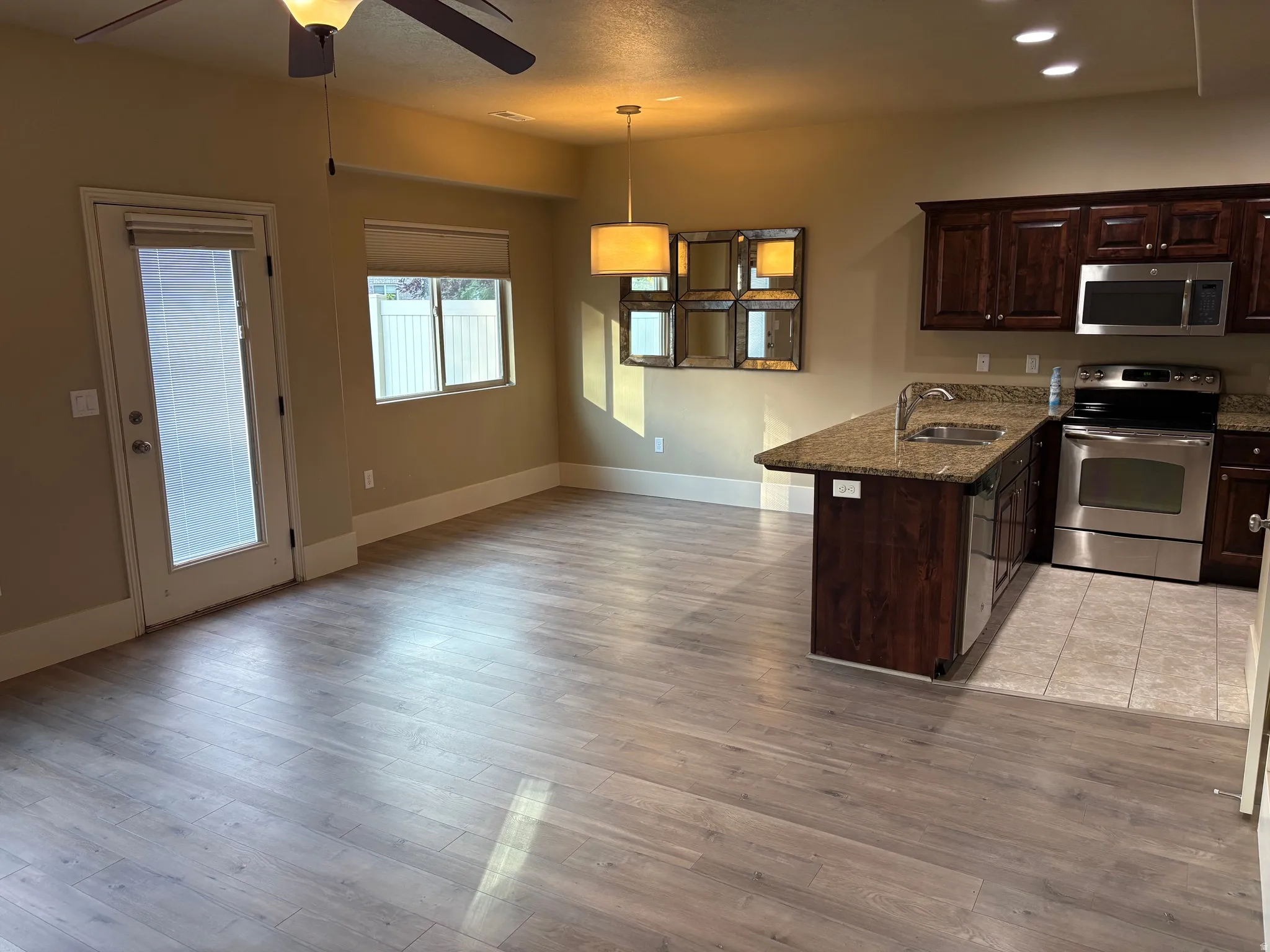 Open concept living area with wood-finish flooring, a kitchen island with sink, and dark wood cabinetry