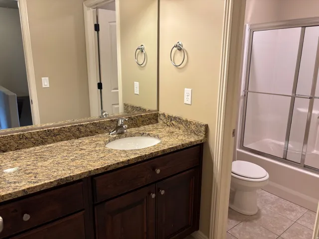 Vanity with a granite-style countertop, undermount sink, and wood-finish cabinetry