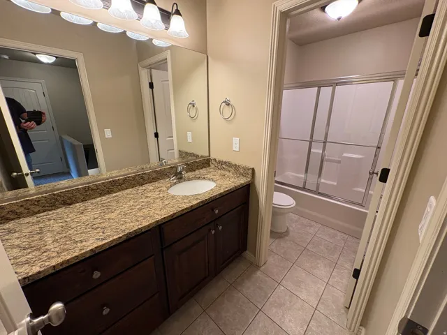 Bathroom with a single vanity, granite countertop, undermount sink, and dark wood cabinetry