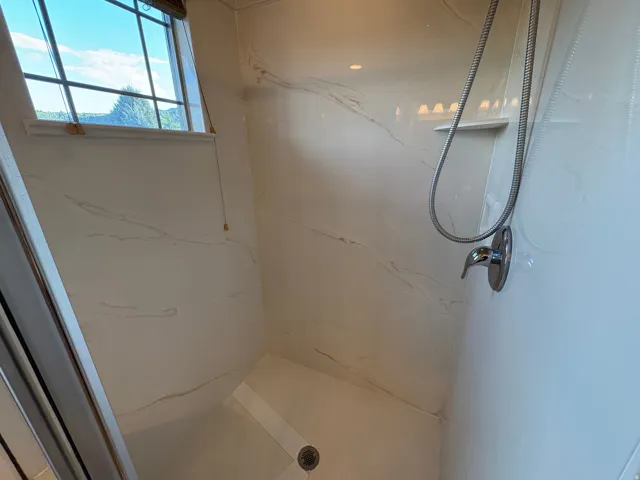 Shower enclosure featuring a built-in bench, integrated shelving, and a chrome shower fixture