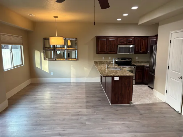 Open-concept living area with wood-finish flooring, recessed lighting, and a window with blinds