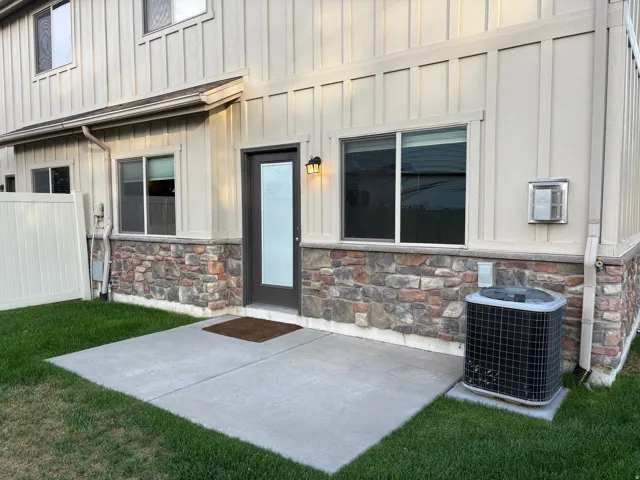 Ground-level patio with concrete surfacing, exterior lighting fixture, and a privacy fence